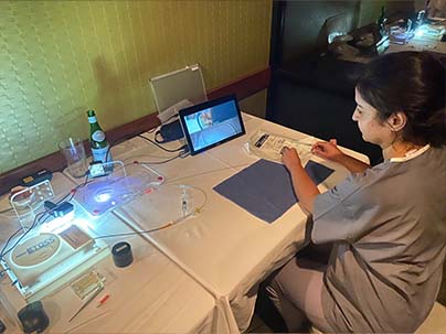 woman dressed in scrubs sitting at a table using guidewire simulator looking at the laptap screen as she moves guidewire through